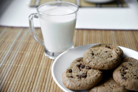 A glass glass with milk on a wooden mat with oatmeal cookies. Afternoon lunch with cookies. Sweet...
