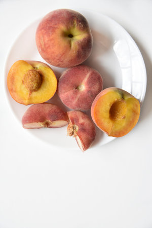 Nectarine and peaches cut into slices on a white plate. Vegetarian food.の写真素材