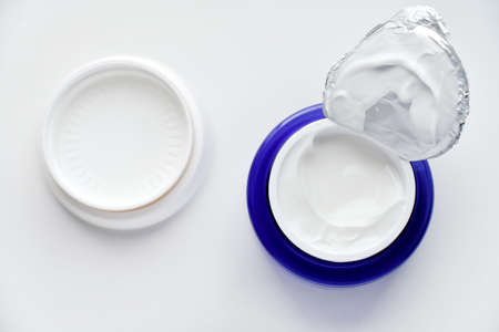 A jar of face cream on a white background. Night cream and hand close-up. Cosmetology concept.の写真素材