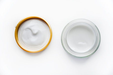 A jar of face cream on a white background. Night cream and hand close-up. Cosmetology concept.
