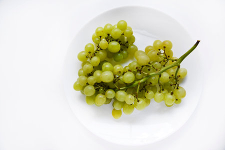 A bunch of green grapes on a white plate close-up. green natural background. Healthy farm healthy food.の写真素材