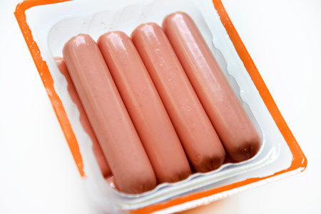 Juicy meat sausages in plastic packaging on a white background. Sausages in the group. Meat semi-finished product in a package.の写真素材