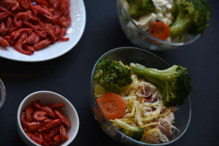 Red dried shrimp and salad in a salad bowl on a black background with forks. Delicious breakfast on a black background salad and shrimp. Black background.の写真素材