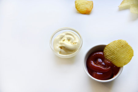Corrugated potato chips with pepper on a white background. Delicious fast food chips. with sauce.