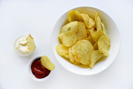 Corrugated potato chips with pepper on a white background. Delicious fast food chips. with sauce.