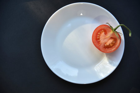 Ripe beautiful tomato fruit on a white plate top view. Delicious tomatoes still life.の写真素材