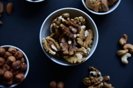 Delicious walnuts in a ceramic bowl on a black background. A delicious breakfast of Juglans regia nuts. healthy eating.の写真素材