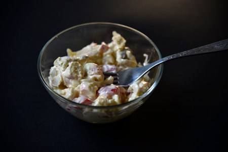 Delicious salad of vegetables and sauces in a salad bowl with a fork. Salad on a black background.の写真素材