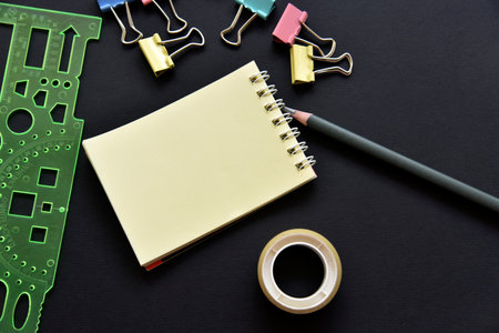 office still life. Pencil and notepad with paper clips on a black background. blank texture. business concept.の写真素材