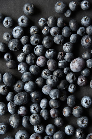 Black blueberries Vaccinium myrtillus on a black background. Growing food.
