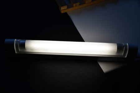 LED lamp on the desk. Glowing fluorescent lamp and LED on a black table. dark background. color...