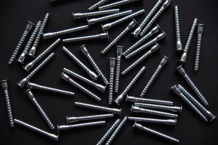 Shiny steel bolts for fixing furniture. Accessories on a black background. . abstract texture background. blank texture.の写真素材