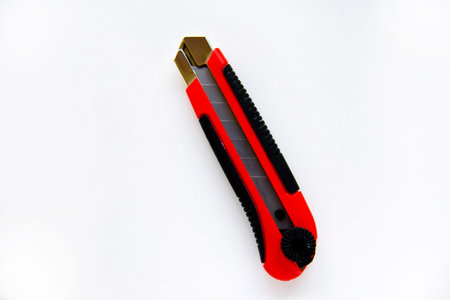 Red stationery knife with blades on a white background. Cutting tool with blades on a white...