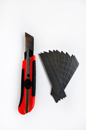 Red stationery knife with blades on a white background. Cutting tool with blades on a white...