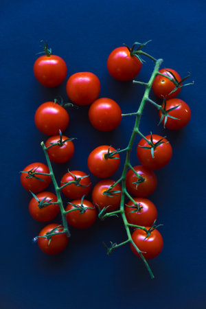 Small cherry tomatoes are yellow and red in a paper container. Small tomatoes on a black background. natural pattern.の写真素材