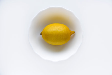 Yellow juicy lemons in a white saucer. Delicious yellow lemons on a white background. Beautiful...