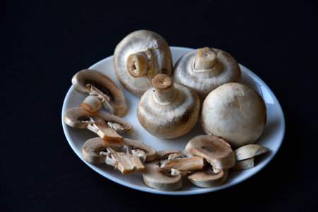 Porcini mushrooms in a white plate on a black background. Fruits of large white champignons close-up. Beautiful mushrooms in a plate. beautiful natural background.の写真素材