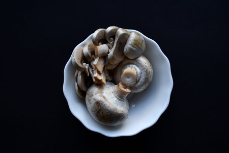 Porcini mushrooms in a white plate on a black background. Fruits of large white champignons...