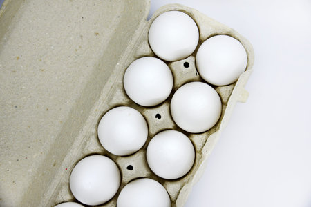 Fresh white chicken eggs in a paper bag. White eggs in a package on a white background. Eggs from...