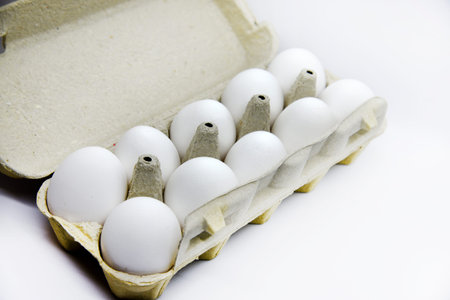 Fresh white chicken eggs in a paper bag. White eggs in a package on a white background. Eggs from...
