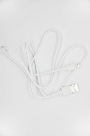 White USB cable for charging the phone on a white background. White cord for charging gadgets....