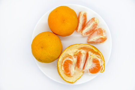 Juicy tangerines on a plate on a white background. Juicy citrus fruits. Slices of tangerines.の写真素材