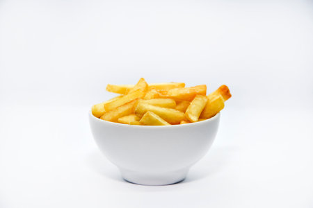 Yellow delicious French fries in white dishes. Fast food on a plate. Fried potatoes. Toasted potato slices on a white background.の写真素材