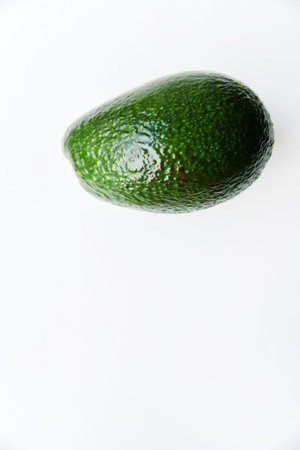 Green avocado fruit on a white background. Juicy avocado fruit close-up.