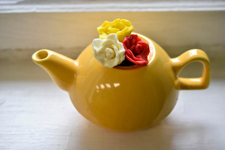 Yellow decorative teapot on the windowsill. Teapot with decorative flowers.の写真素材