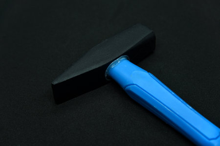 Construction hammer on a black background. A carpenter's hammer with a blue handle on a black background.の写真素材