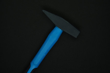 Construction hammer on a black background. A carpenter's hammer with a blue handle on a black...