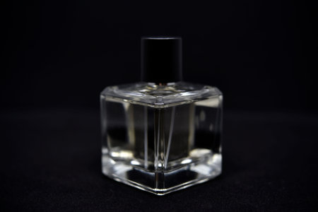 A glass perfume bottle on a black background. A bottle of perfume in close-up. Perfume.