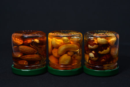 Mixed nuts in glass jars on a black background, close-upの写真素材