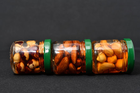 Mixed nuts in glass jar on black background. Healthy food concept.の写真素材