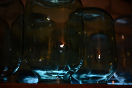 Empty glass jars on a shelf in a dark room, close-upの写真素材