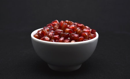 Pomegranate seeds in a bowl on a black background.の写真素材