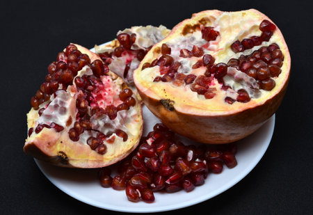 Pomegranate fruit divided into slices on a white plate. Delicious pomegranate fruit.の写真素材