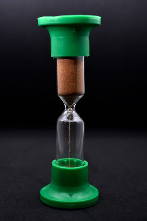Glass hourglass on a black background. Multicolored glass hourglass.