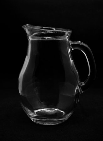 An empty glass milk jug. A glass vessel on a black background.の写真素材