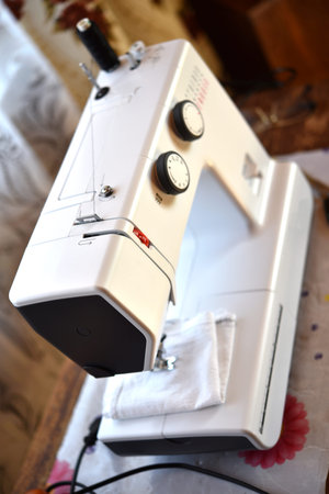 A white sewing machine in the room. Processing of clothes with a sewing machine.