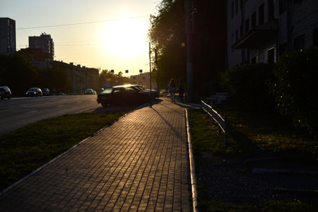 Summer city street in the setting sun. People walking away into the distance. City summer road and sidewalk.の写真素材