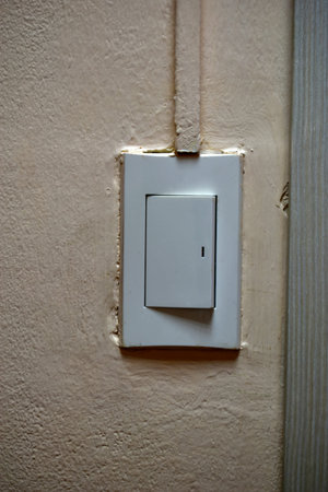 Household light switch on the wall. White plastic switch.