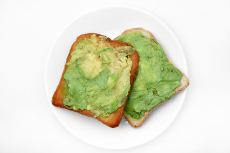 Avocado pasta on fried toast. Vegetables spread on bread. Vegan breakfast on a white plate.の写真素材