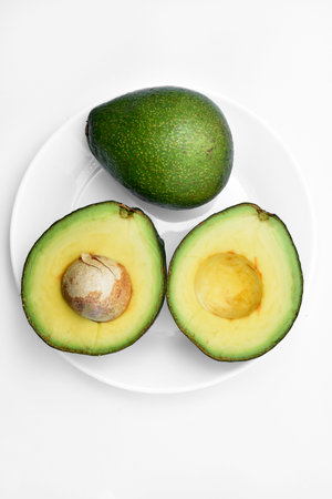 Sliced green avocado on a white background. Pieces of green vegetable on a white plate. Delicious...