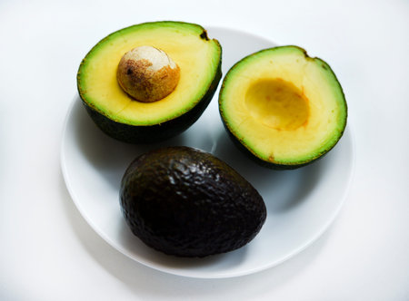 Sliced green avocado on a white background. Pieces of green vegetable on a white plate. Delicious...