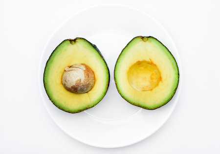 Sliced green avocado on a white background. Pieces of green vegetable on a white plate. Delicious food for a vegan.の写真素材