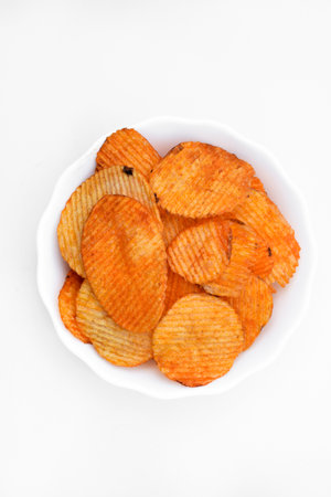 Red pieces of fried potatoes in a plate. Peppery chips on a white background.の写真素材