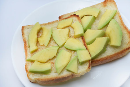 Fried toast with slices of green avocado. A delicious lunch of bread and ripe avocado.