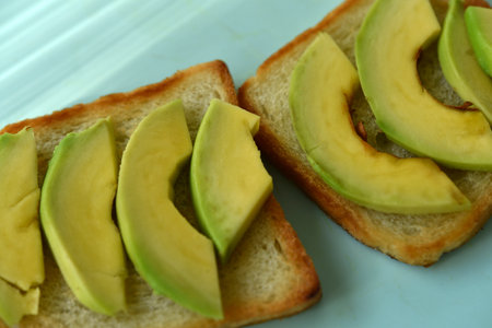 Fried toast with slices of green avocado. A delicious lunch of bread and ripe avocado.の写真素材