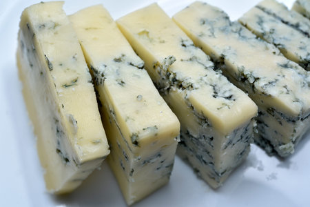 Sliced cheese with blue mold on a white plate. Delicious breakfast with cheese.